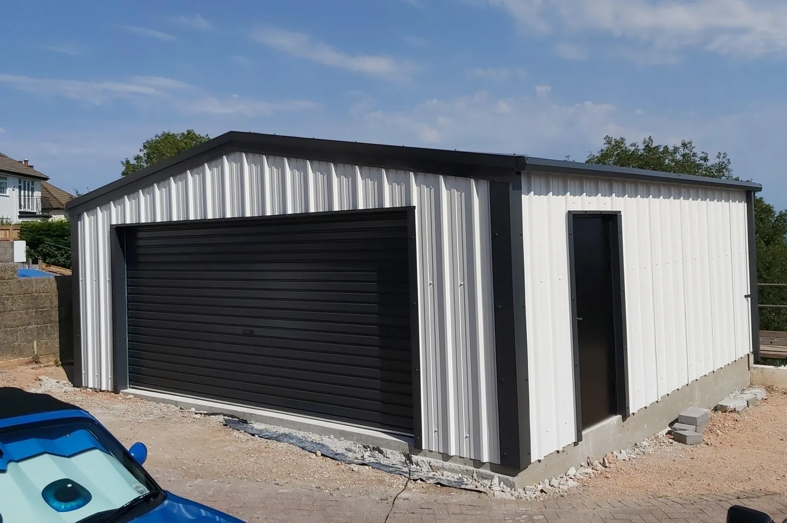 White clad steel garage with a black roller door