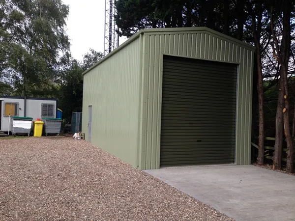 Tall pale green steel garage with a dark roller door