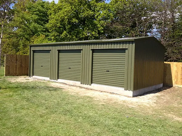 Triple steel garage in green cladding with three roller doors